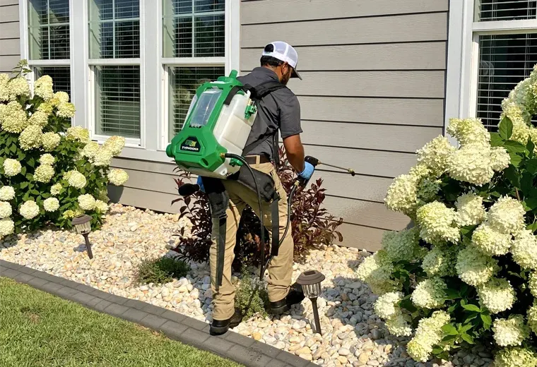 tech spraying exterior of sided house